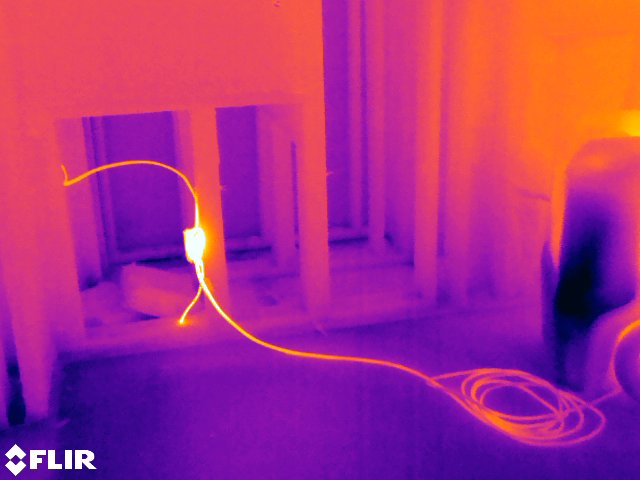 FLIR thermal image revealing a heat signature tracing hidden wiring behind an unfinished wall